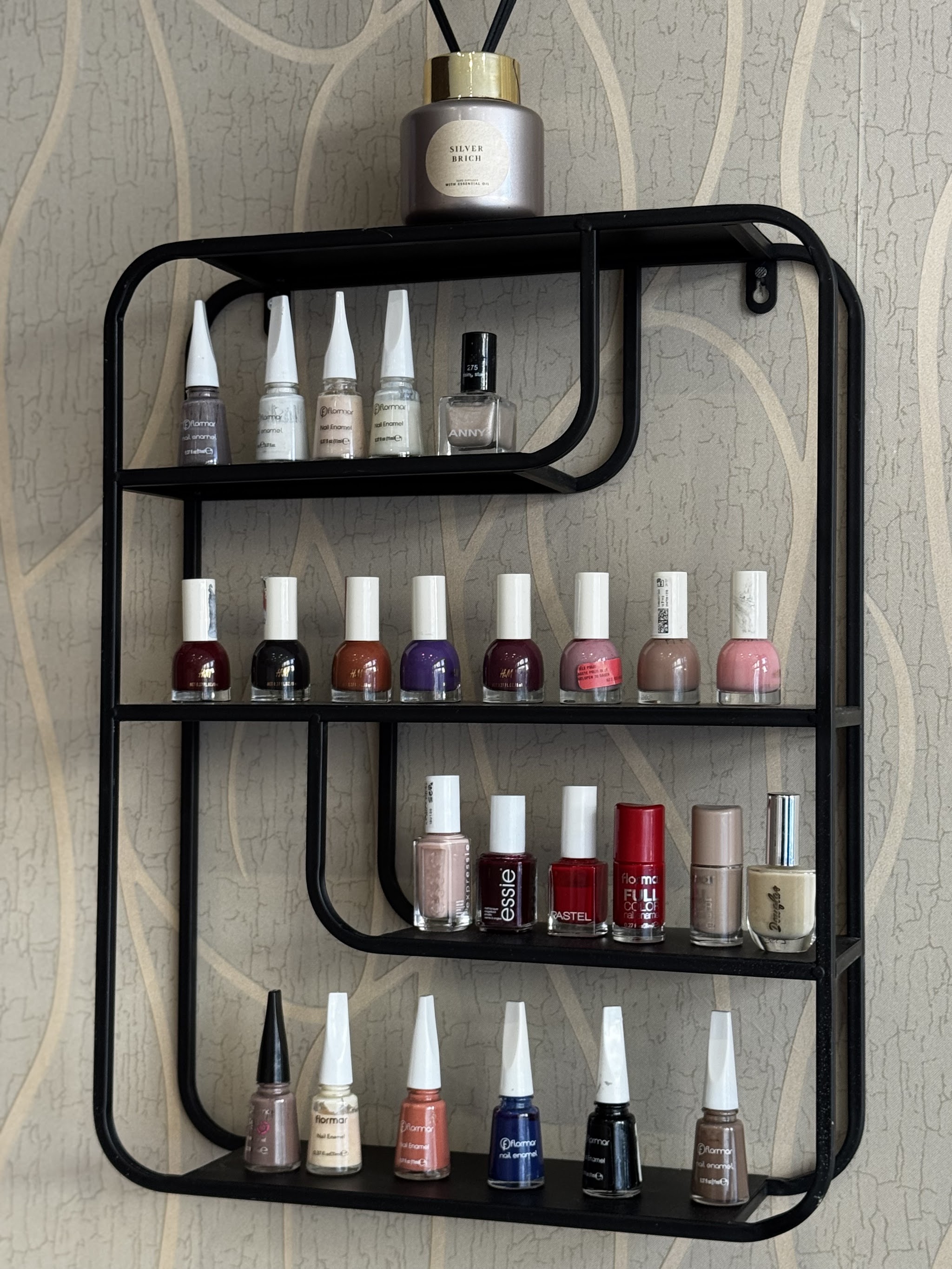 Zwart wandrek met flesjes nagellak en een geurstokjes-diffuser