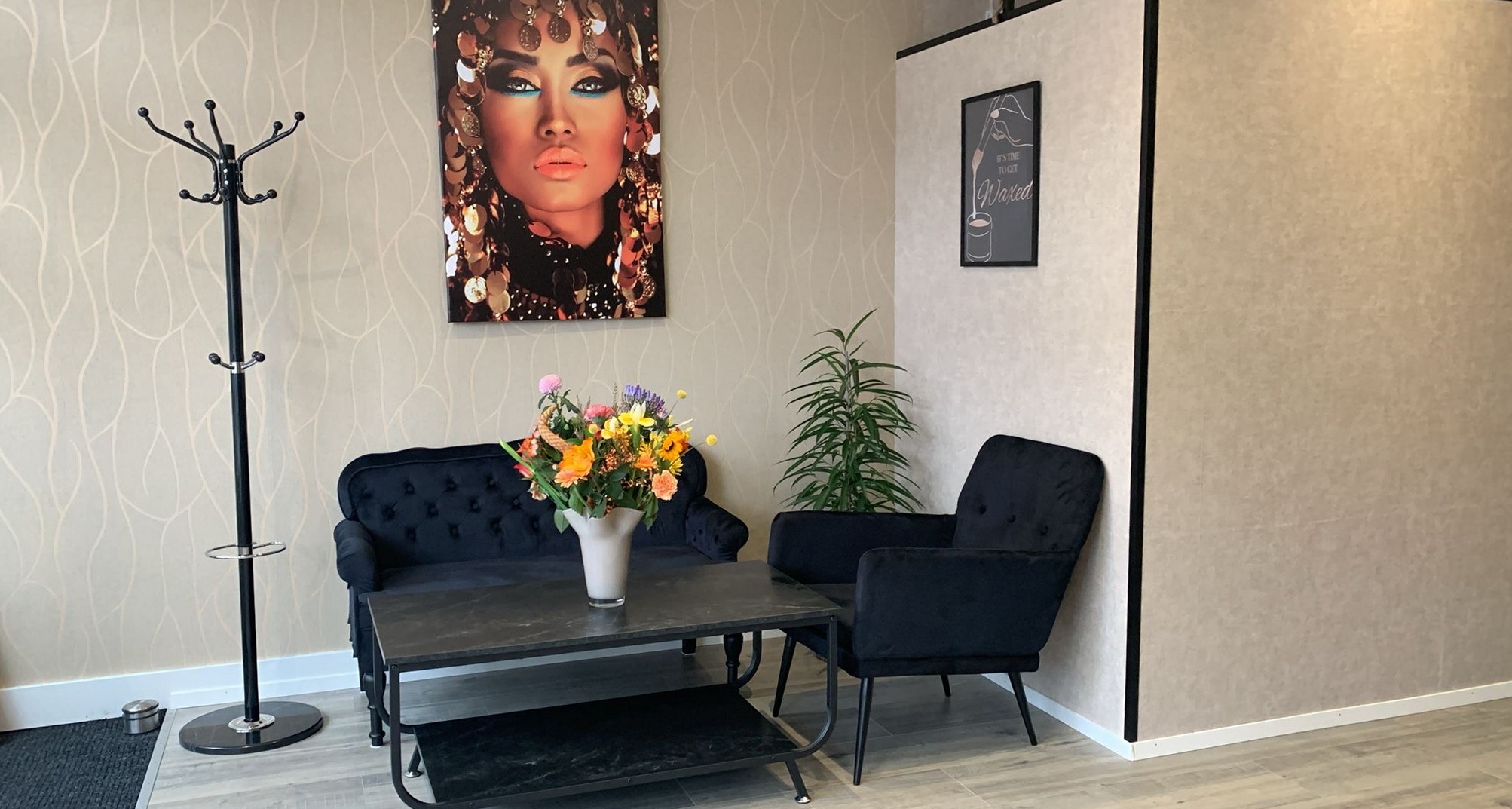 De zithoek van de salon met een bank, een fauteuil en bloemen